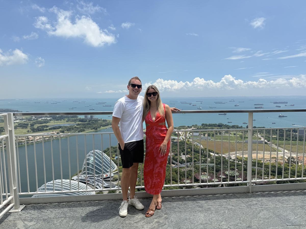 Will Tjernlund and Kelsey at the Marina Bay Sands SkyPark in Singapore, with Gardens by the Bay and the Singapore Strait shipping lanes behind